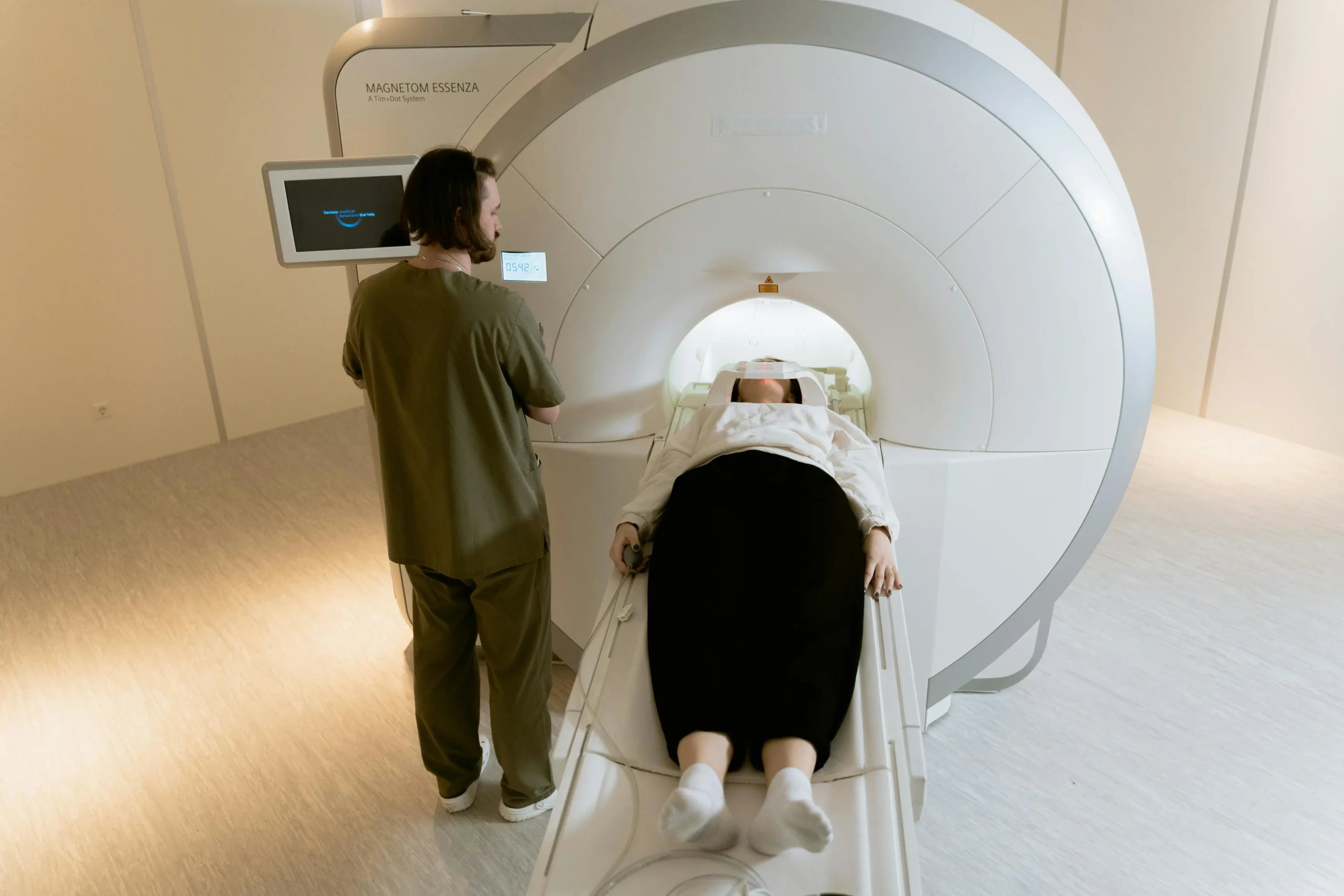 A female patient begins head MRI exam, radiologist sets appropriate scan parameters